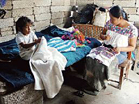 Photo: Virginia Bocato de la Pila embroiders while her daughter Mariel plays