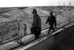 Two children cross a dry irrigation canal